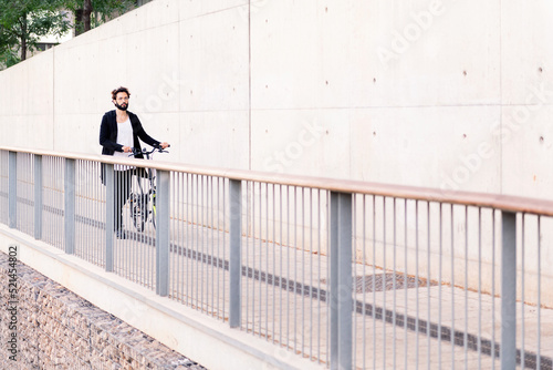 man walking in front of a white wall with his bike