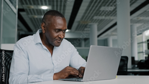 African american businessman work on laptop at office chatting online young woman trainee come to adult colleague analyze startup internet project approve commercial idea thumb up agreeing shake hands