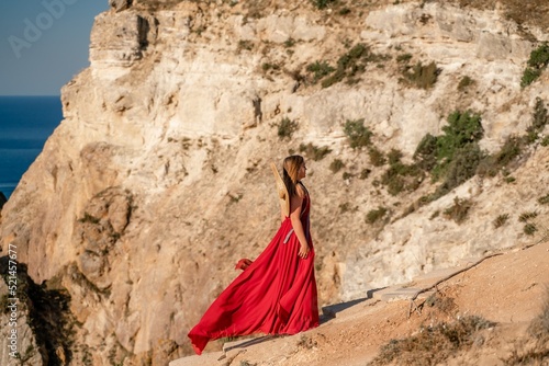 A woman in a red flying dress fluttering in the wind, against the backdrop of the sea.