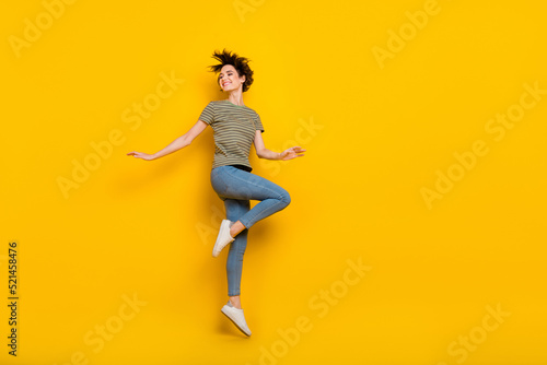 Full length photo of sweet shiny lady wear striped t-shirt jumping high looking empty space isolated yellow color background