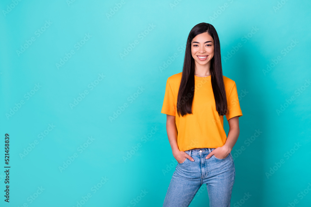 Photo of nice pretty gorgeous beaming girl with long hairdo dressed yellow t-shirt arms in pockets isolated on turquoise color background Photo of nice pretty gorgeous beaming girl with long hairdo dressed yellow t-shirt arms in pockets isolated on turquoise color background