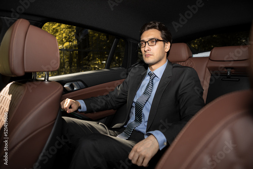 Successful handsome businessman sitting in the passenger seat in his luxury car and driving to a business meeting © Vitaliy