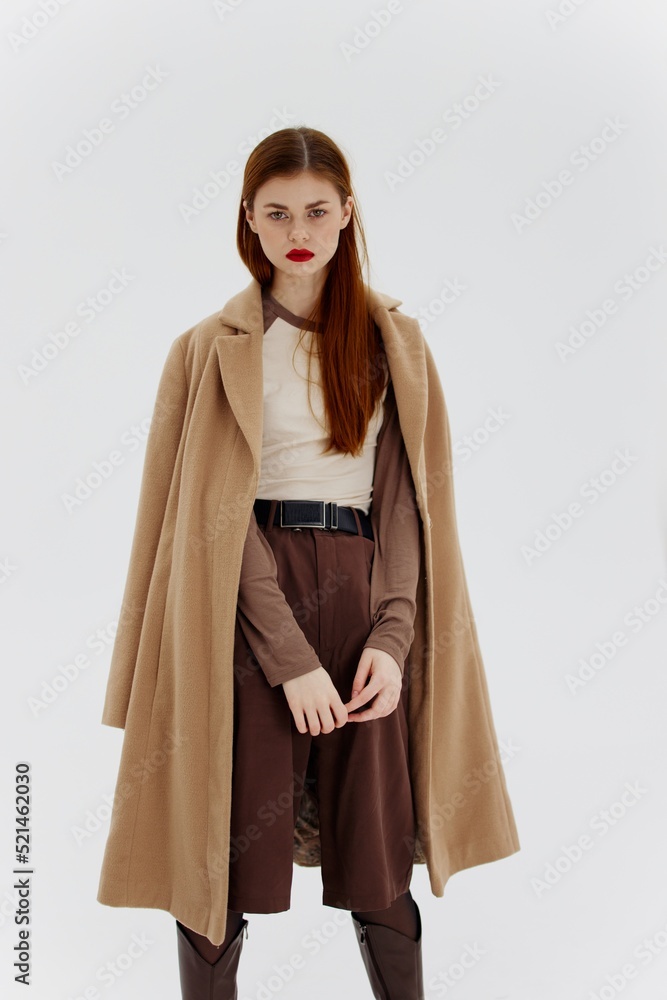 A red-haired lady in a beige coat on a white background. Advertising for brands showrooms catalog of clothing for women A red-haired lady in a beige coat on a white background. Advertising for brands showrooms catalog of clothing for women