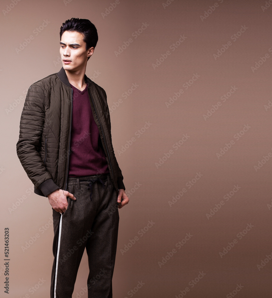 young pretty asian man posing in fashion style on light brown background, lifestyle people concept young pretty asian man posing in fashion style on light brown background, lifestyle people concept