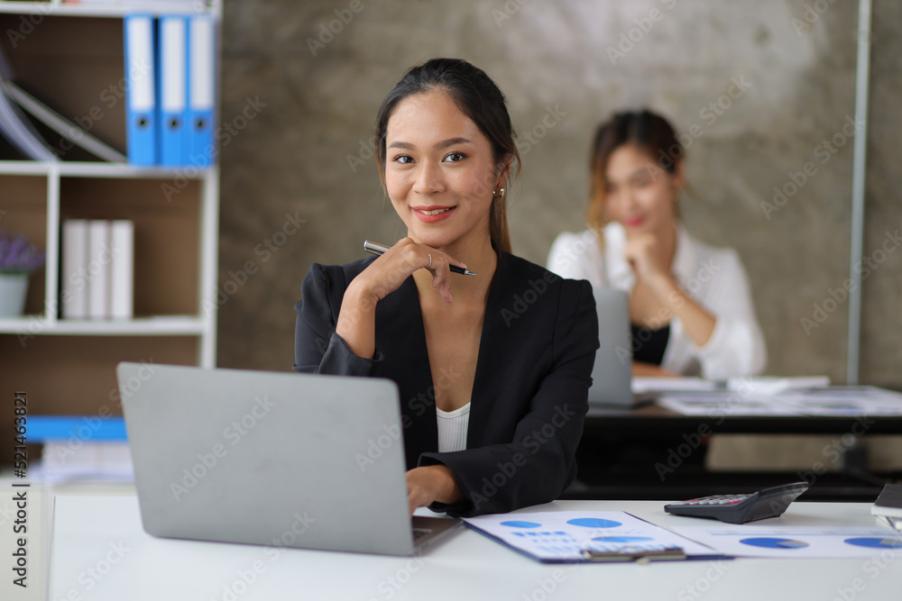 Portrait of a businesswoman or female manager working on a laptop in the office. Looking at camera. Portrait of a businesswoman or female manager working on a laptop in the office. Looking at camera.