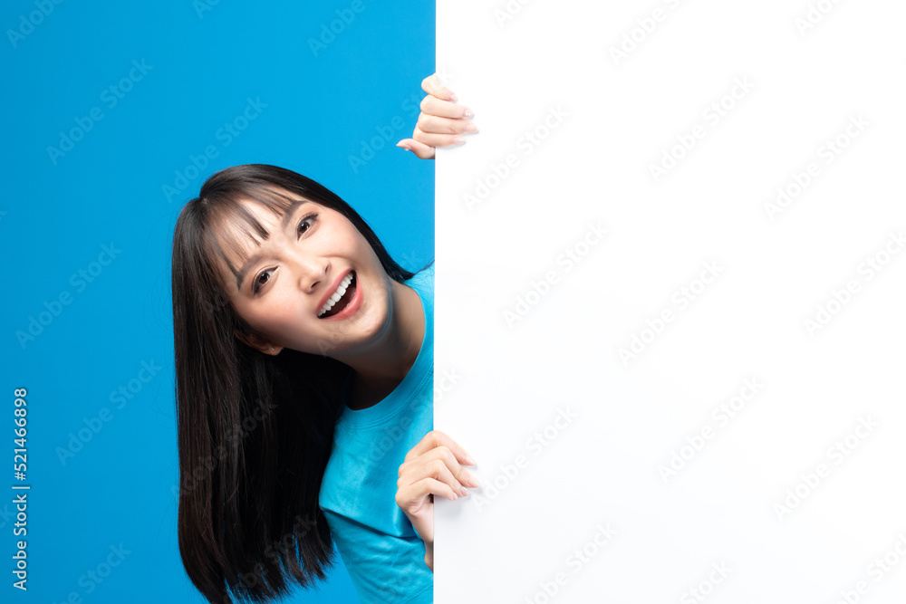 Portrait of smiling asian woman holding empty blank board on blue studio background. Happy young girl standing with white square paper card for text and showing card to camera. Portrait of smiling asian woman holding empty blank board on blue studio background. Happy young girl standing with white square paper card for text and showing card to camera.