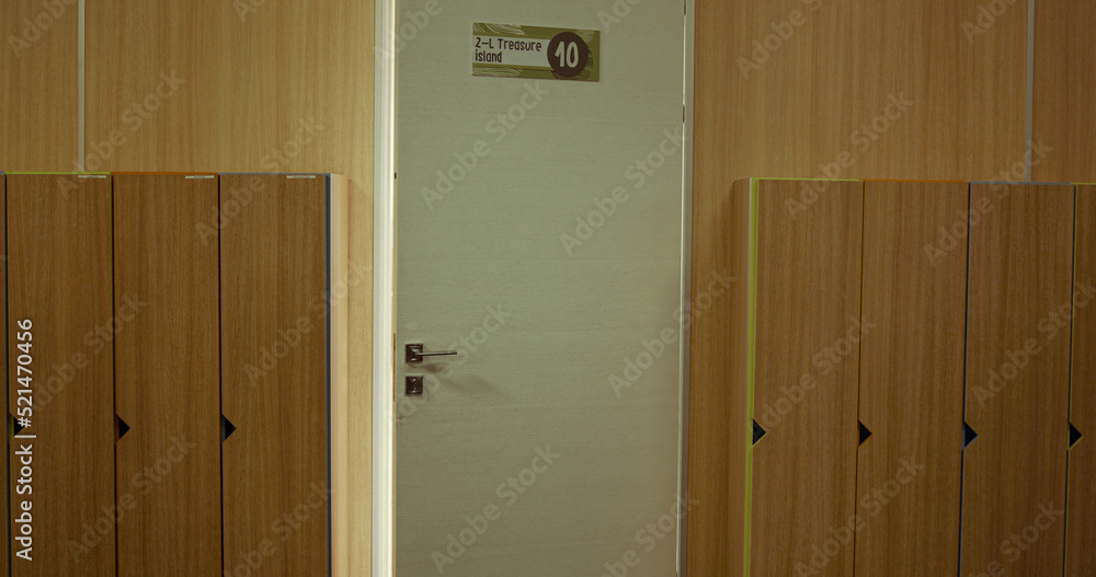 Closeup white classroom door open in empty hall. School interior with lockers. Stock Photo