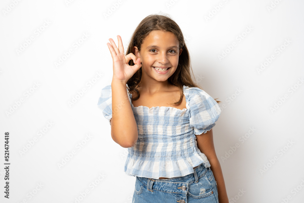 Portrait image of very happy amazed smiling brunette little cute girl, casual clothing, showing okay or zero hand sign gesture, isolated over white background with copy space. Portrait image of very happy amazed smiling brunette little cute girl, casual clothing, showing okay or zero hand sign gesture, isolated over white background with copy space.