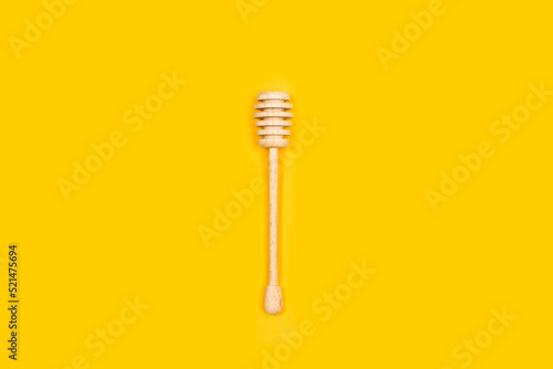 Batuta de madera para miel sobre un fodo amarillo brillante liso y aislado. Vista superior y de cerca. Copy space