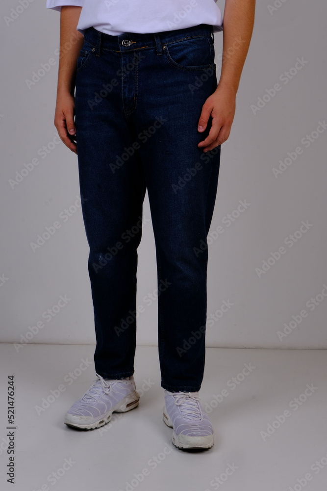 slender man in spring street clothes: skinny blue jeans and a white T-shirt. body parts: elastic male ass. concept: men's health and hemorrhoid pain. image for clothing catalog slender man in spring street clothes: skinny blue jeans and a white T-shirt. body parts: elastic male ass. concept: men's health and hemorrhoid pain. image for clothing catalog