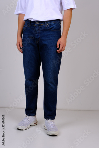 slender man in spring street clothes: skinny blue jeans and a white T-shirt. body parts: elastic male ass. concept: men's health and hemorrhoid pain. image for clothing catalog