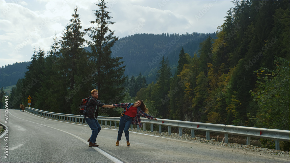 Backpackers dancing mountains road. Cute couple hold hands on nature travel trip