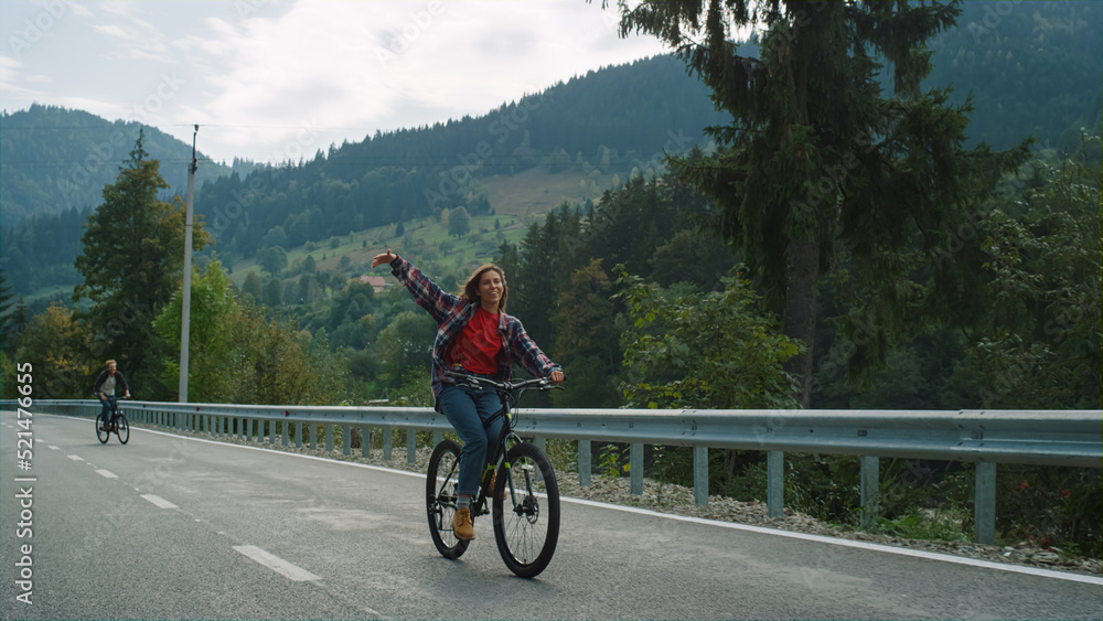 Obraz premium Friends cycling forest road on sport bikes. Carefree travelers enjoy mountains.