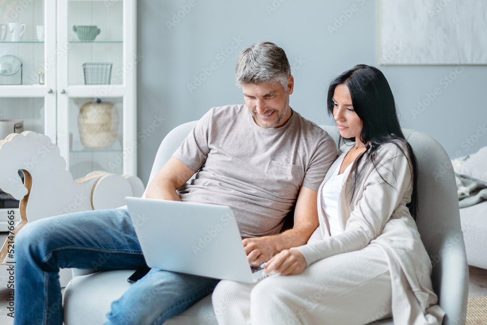 husband and wife using a laptop in their living room. husband and wife using a laptop in their living room.