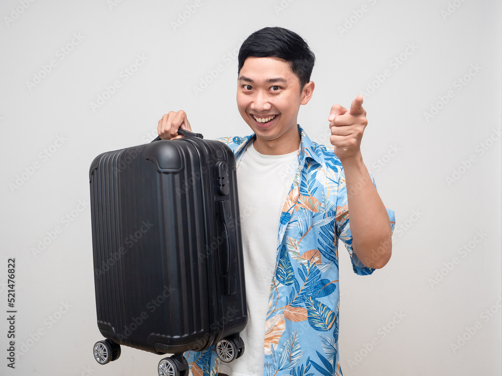 Cheerful man beach shirt hold luggage smiling point finger at you Cheerful man beach shirt hold luggage smiling point finger at you