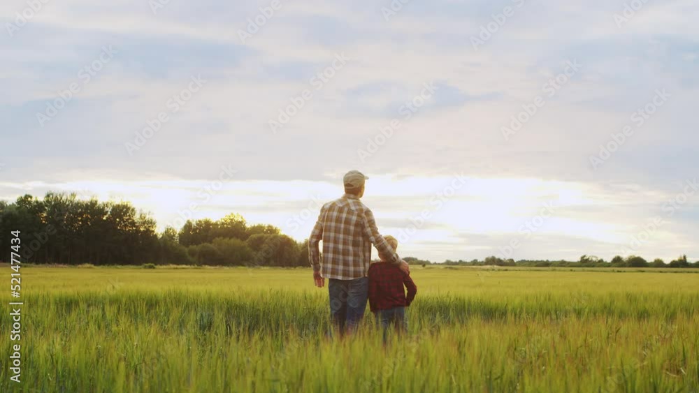 Farmer and his son in front of a sunset agricultural landscape. Man and a boy in a countryside field. Fatherhood, country life, farming and country lifestyle concept. Farmer and his son in front of a sunset agricultural landscape. Man and a boy in a countryside field. Fatherhood, country life, farming and country lifestyle concept.