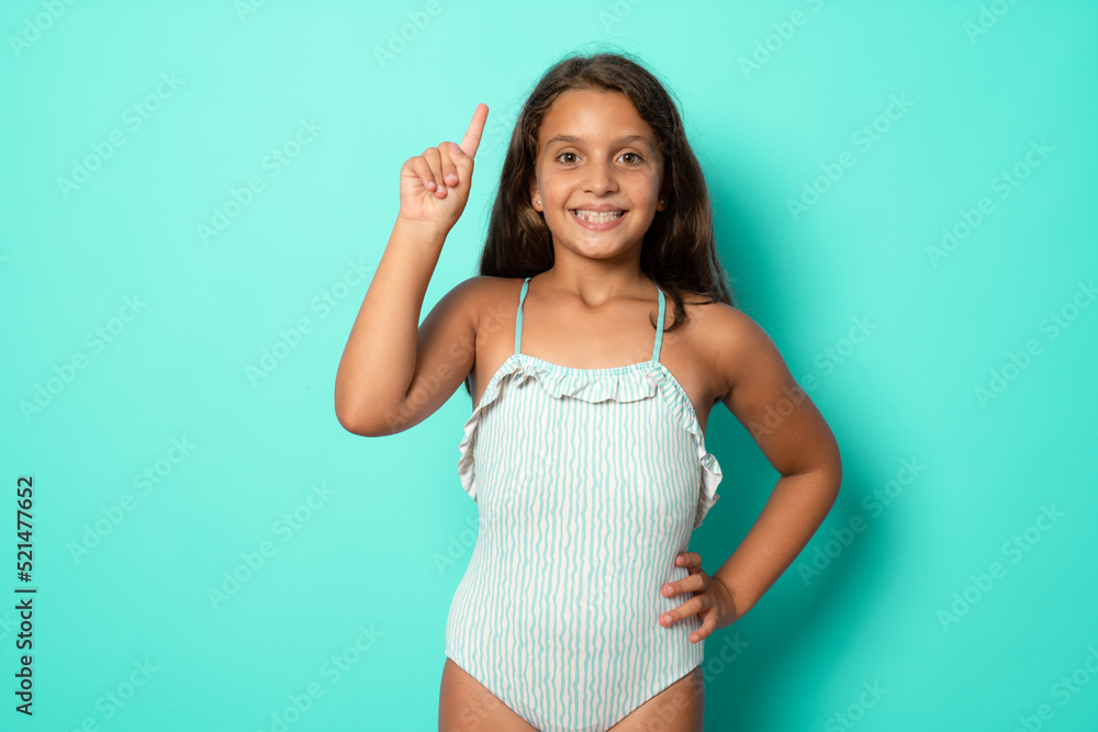Brunette hispanic girl in swimsuit showing and pointing up with finger number one while smiling confident and happy. Brunette hispanic girl in swimsuit showing and pointing up with finger number one while smiling confident and happy.