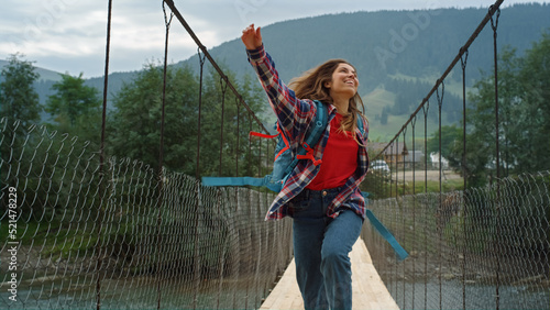 Happy traveler jumping mountains on river bridge. Emotional woman walk on hike.