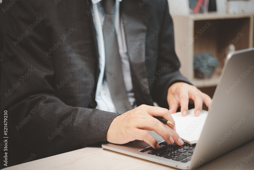Man person using keyboard computer laptop holding pen and book on desk. Man person using keyboard computer laptop holding pen and book on desk.