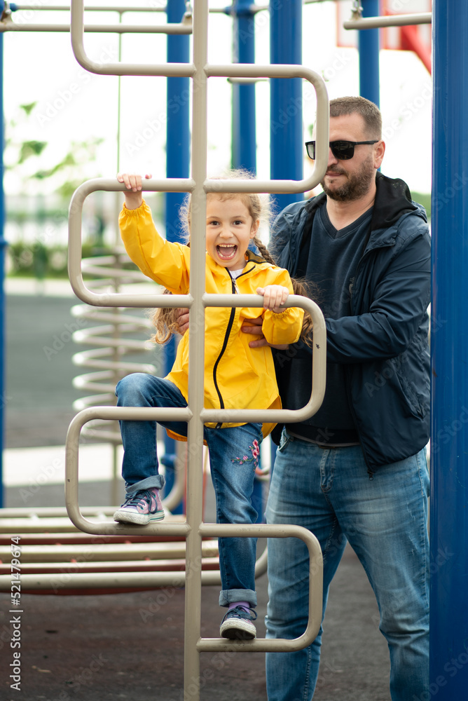 Obraz premium Cute girl with her dad on the sports field. Girl tries to work out on sports simulators and has fun. Childhood. Healthy lifestyle. Family. Conception.