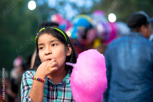 Smiling girl eating cotton Candy at the fair. © SALMONNEGRO