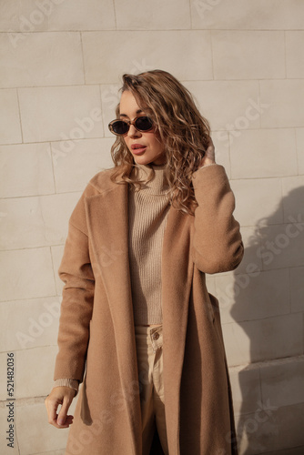 portrait of a style woman walking, enjoys a wonderful atmosphere of a vacation in fall time. The girl is wearing a urban beige sweater,  