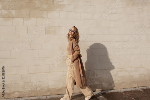 portrait of a style woman walking, enjoys a wonderful atmosphere of a vacation in fall time. The girl is wearing a urban beige sweater,  