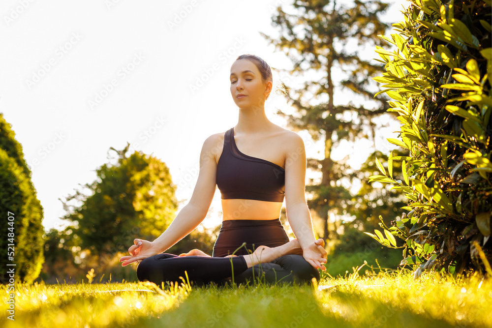 Young peaceful woman sitting in lotus pose, breathing and meditating ...