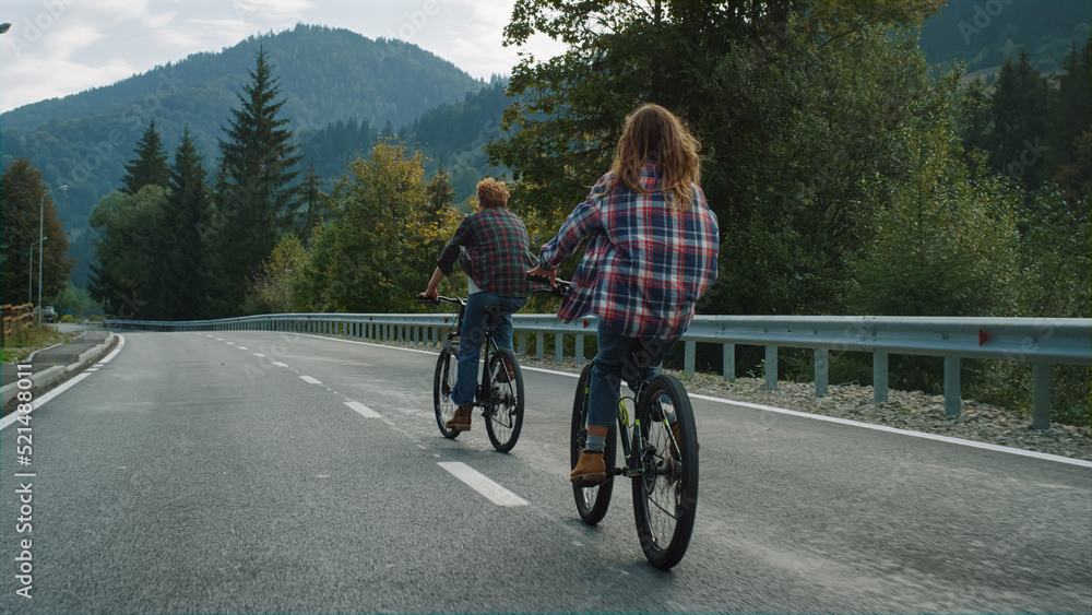 Couple riders cycling mountains together on highway road. Travelers enjoy bikes.