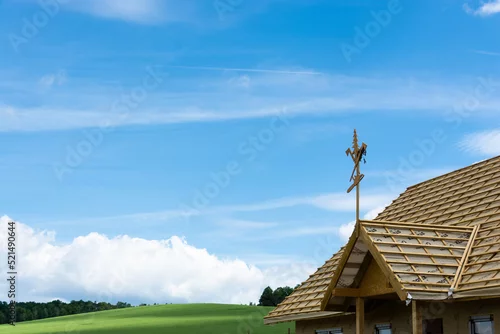 Obraz budowa domu, wiecha na dachu, w tle pola i niebieskie niebo