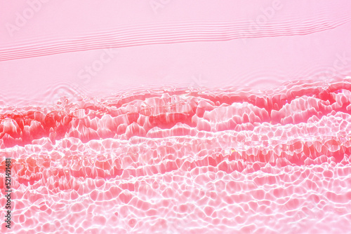 Cosmetic background, texture of transparent pink water with seething ripples , waves