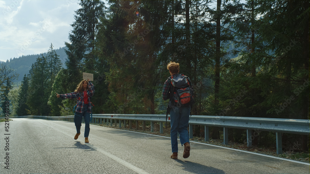 Backpackers standing mountain road outdoors. Hitchhikers wave hands on holiday. Backpackers standing mountain road outdoors. Hitchhikers wave hands on holiday.