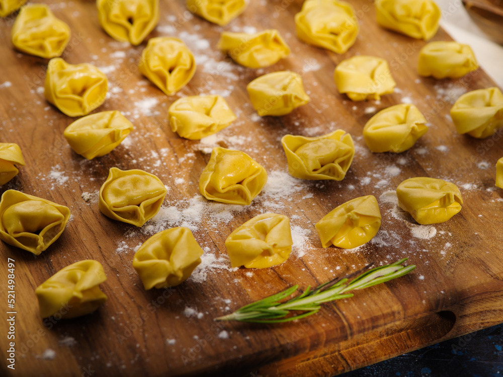 Macro shot. Homemade delicious dumplings stuffed with minced meat on a wooden cutting board and a sprig of rosemary. Culinary background. Home kitchen. Macro shot. Homemade delicious dumplings stuffed with minced meat on a wooden cutting board and a sprig of rosemary. Culinary background. Home kitchen.