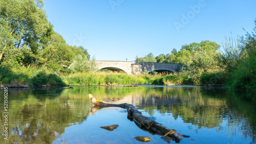 Fluss mit Brücke die sich im Wasser spiegelt und einem Baum im Vordergrund © Jonas 