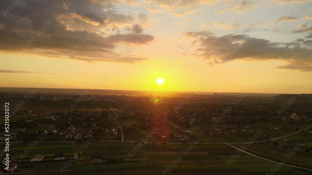 Aerial landscape view of village houses and distant green cultivated agricultural fields with growing crops on bright summer evening Aerial landscape view of village houses and distant green cultivated agricultural fields with growing crops on bright summer evening