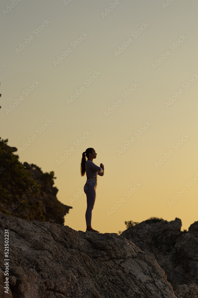 Young woman practice yoga and meditation near the sea at sunrise, healthy lifestyle concept