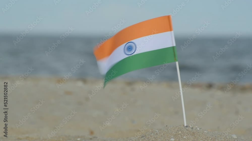 Flag of India on sandy beach on sea and waves background. Indian flag blowing in the wind, border area. Flag of India on sandy beach on sea and waves background. Indian flag blowing in the wind, border area.