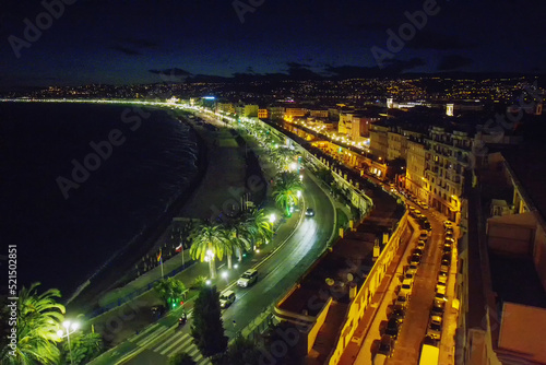 Amazig View on Nice    Promenade des Anglais   - photo from Colline du Chateau .  People walking  and electric lights on - sunset  in  capital of french Riviera .  Lights burning.