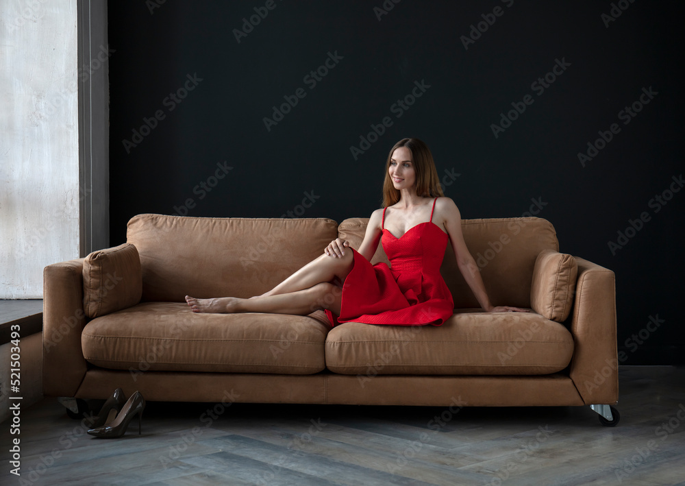 young beautiful woman sitting on a sofa near the window young beautiful woman sitting on a sofa near the window