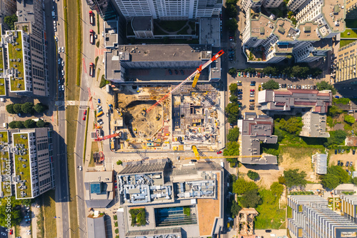 Construction site in the developed city. Engineers, crane operators, and construction workers seen from drone perspective. High quality photo
