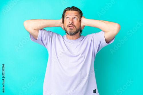 Senior dutch man isolated on blue background frustrated and covering ears