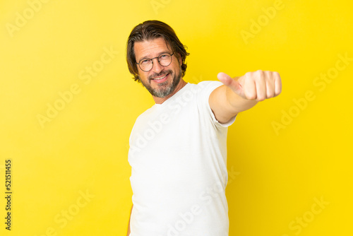Senior dutch man isolated on yellow background giving a thumbs up gesture