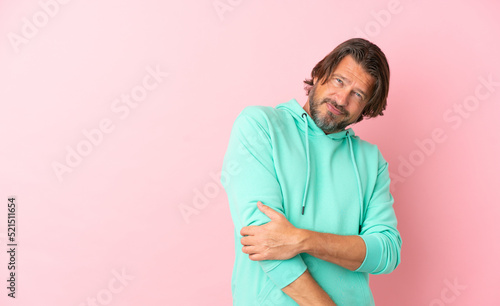 Senior dutch man isolated on pink background laughing