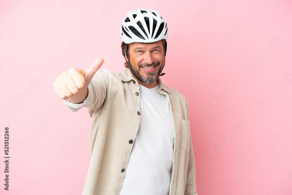 Senior dutch man with bike helmet isolated on pink background giving a thumbs up gesture Senior dutch man with bike helmet isolated on pink background giving a thumbs up gesture
