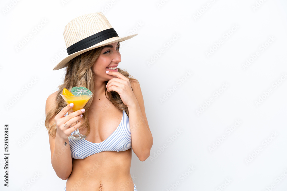 Young woman holding cocktail and wearing a bikini isolated on white background thinking an idea and looking side Young woman holding cocktail and wearing a bikini isolated on white background thinking an idea and looking side