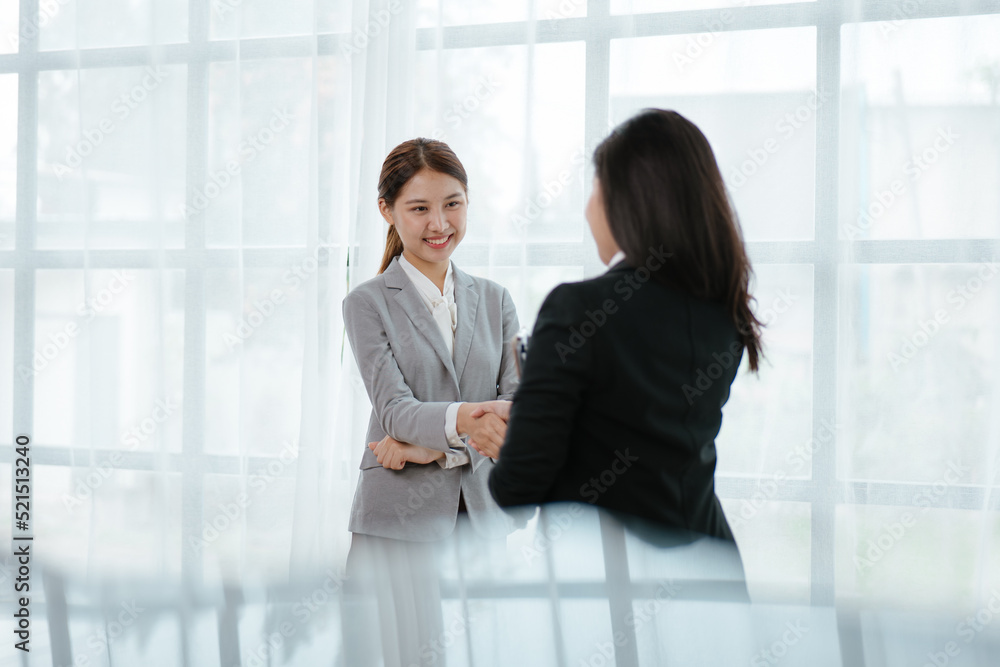 Business woman standing and hand shaking in office Business woman standing and hand shaking in office