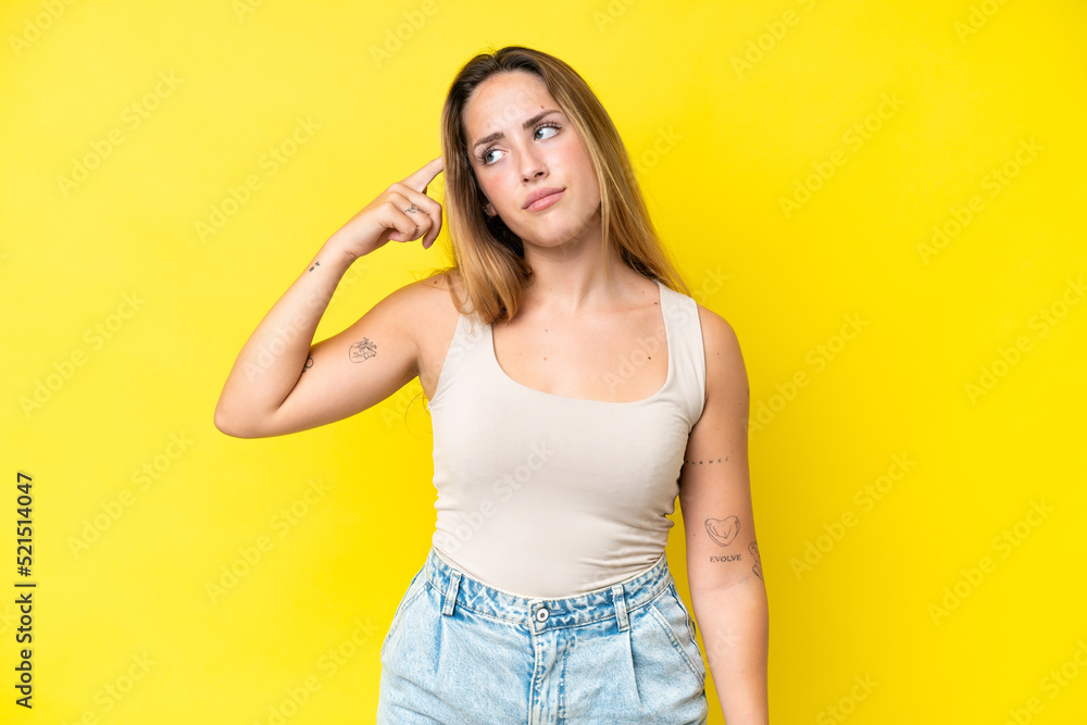 Young caucasian woman isolated on yellow background making the gesture of madness putting finger on the head Young caucasian woman isolated on yellow background making the gesture of madness putting finger on the head