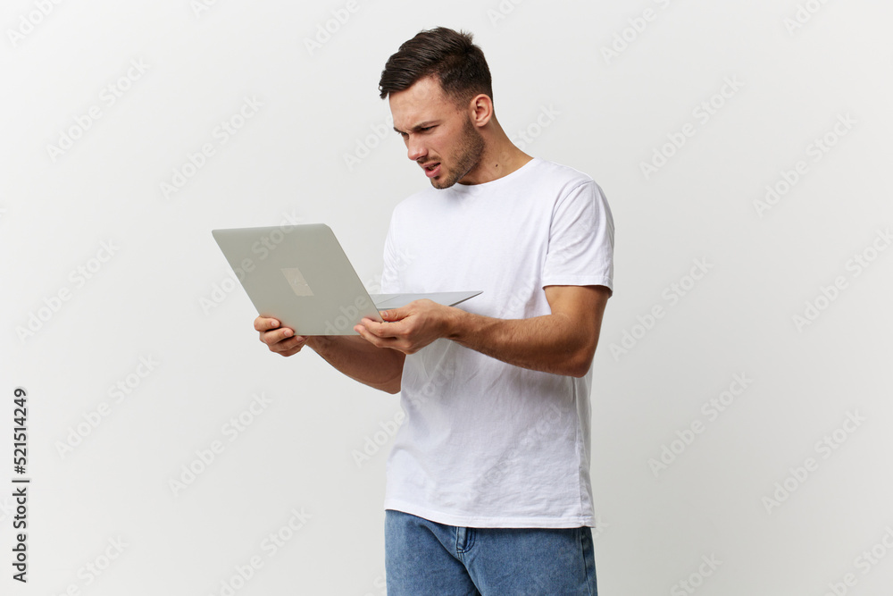 Unhappy angry tanned handsome man in basic t-shirt have problem with broken laptop posing isolated on over white studio background. Copy space Banner Mockup. Electronics repair IT concept