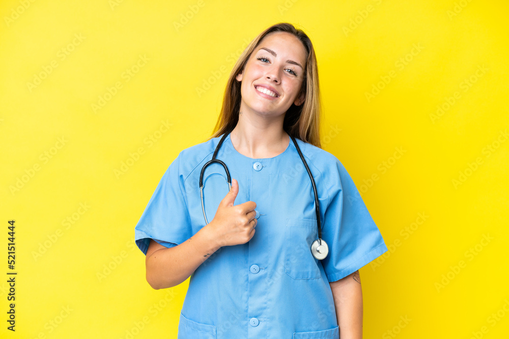 Young surgeon nurse woman isolated on yellow background giving a thumbs up gesture Young surgeon nurse woman isolated on yellow background giving a thumbs up gesture