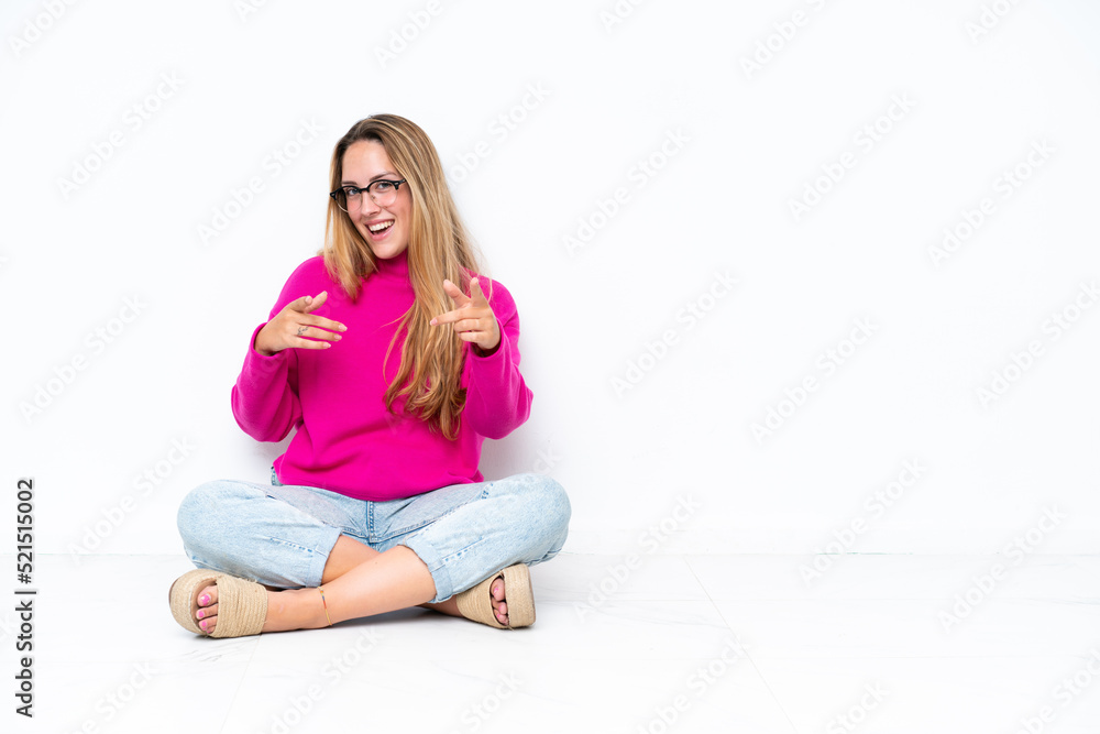 Young caucasian woman sitting on the floor isolated on white background pointing to the front and smiling Young caucasian woman sitting on the floor isolated on white background pointing to the front and smiling